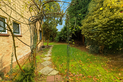 Sonnige tuinpad met boogtralis.png